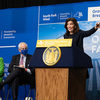 纽约州州长凯西·霍克尔（Kathy Hochul）在戴斯（Dais）后面说话时用手示意。在背景中，一个大横幅指出，“纽约的第一个离岸农场”南叉风电场的2022年开创性。